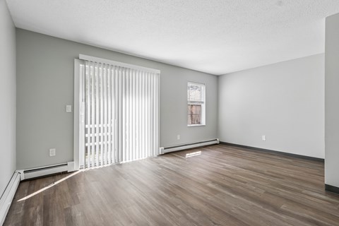 A room with wooden flooring and a window with blinds.