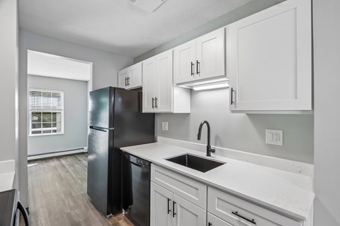A kitchen with black and white cabinets and a black fridge.