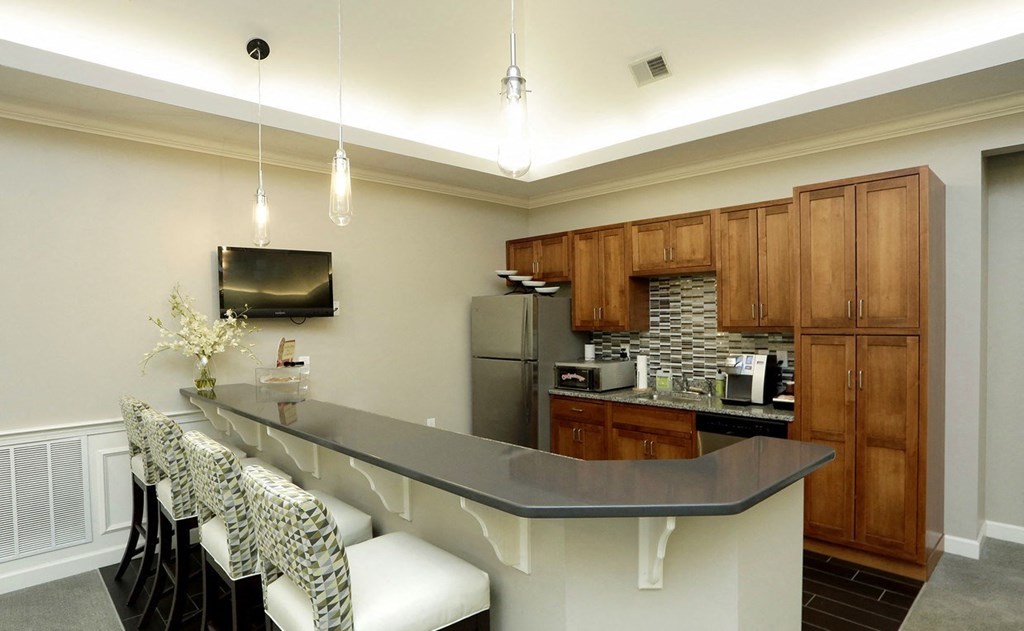 a kitchen with a bar with chairs and a refrigerator