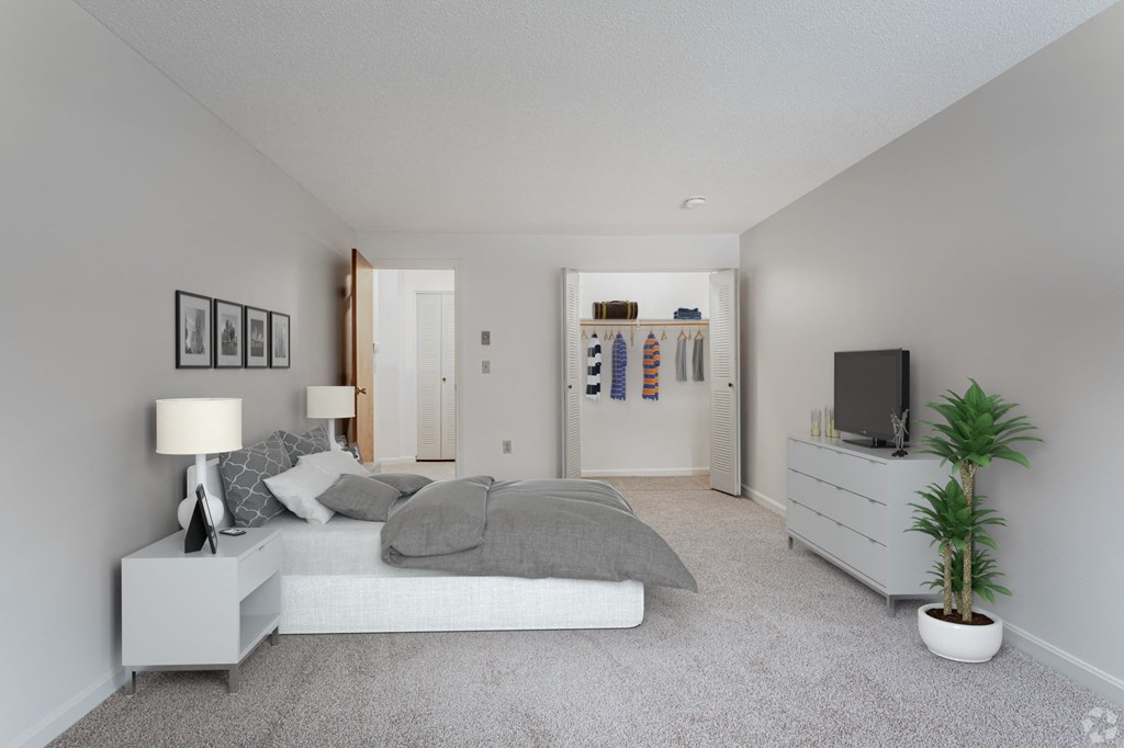 A bedroom with a bed, nightstand, and a plant.