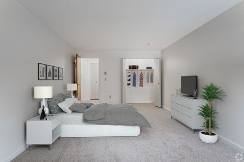 A bedroom with a bed, nightstand, and a plant.