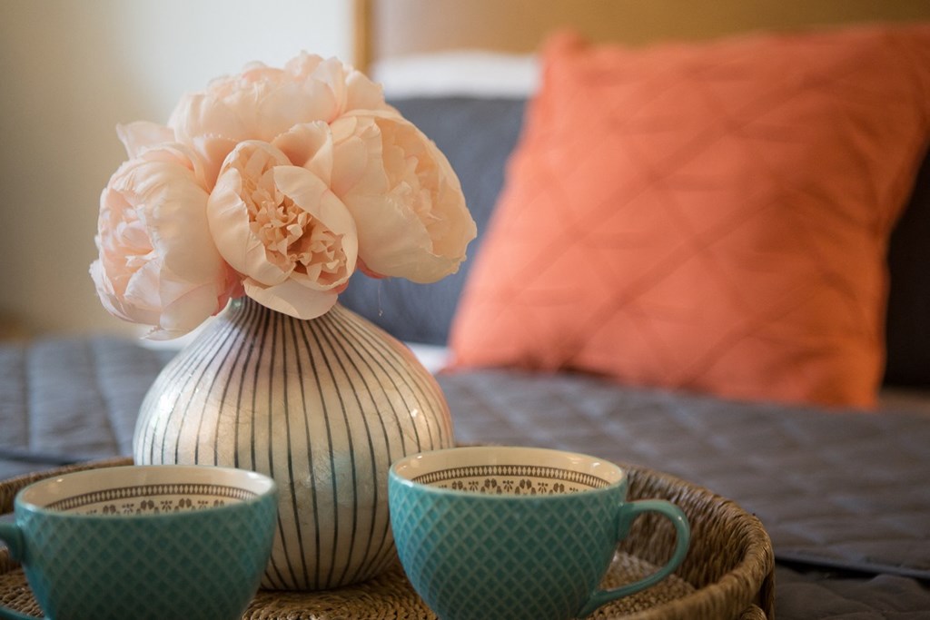 a table with coffee cups and a vase with a flower on it