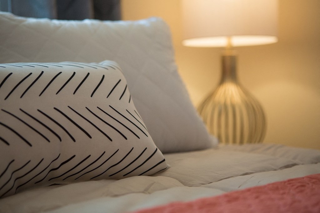 a bed with black and white pillows and a lamp
