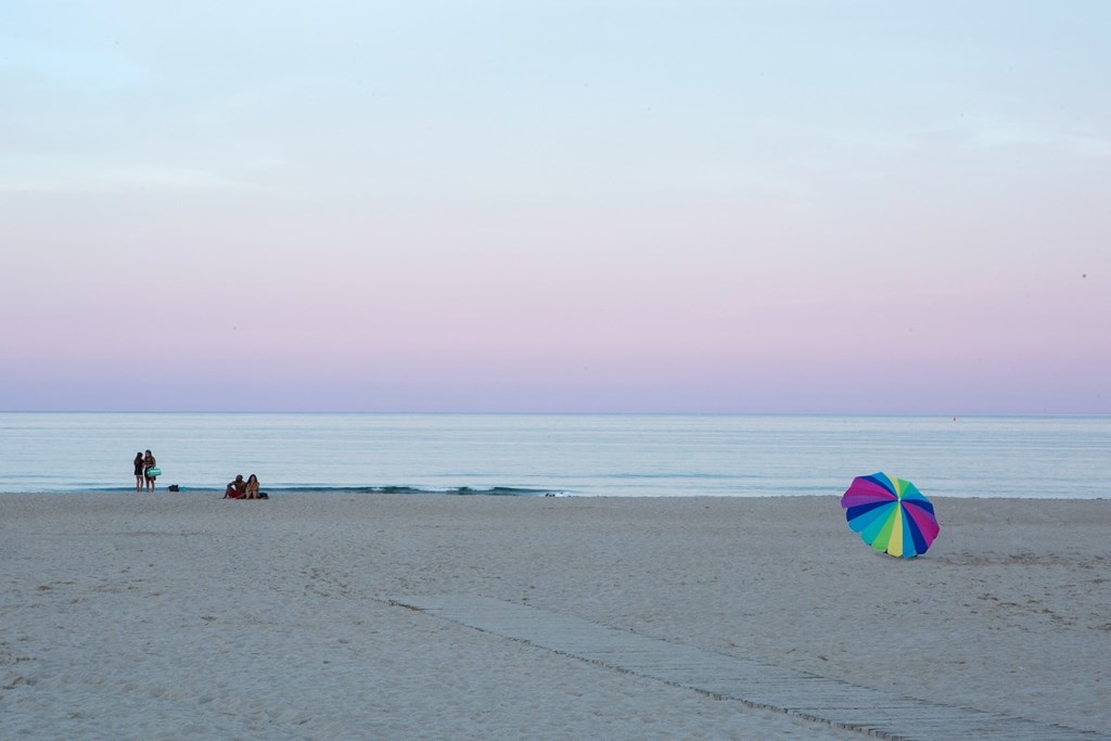 a beach umbrella on the beach at sunset