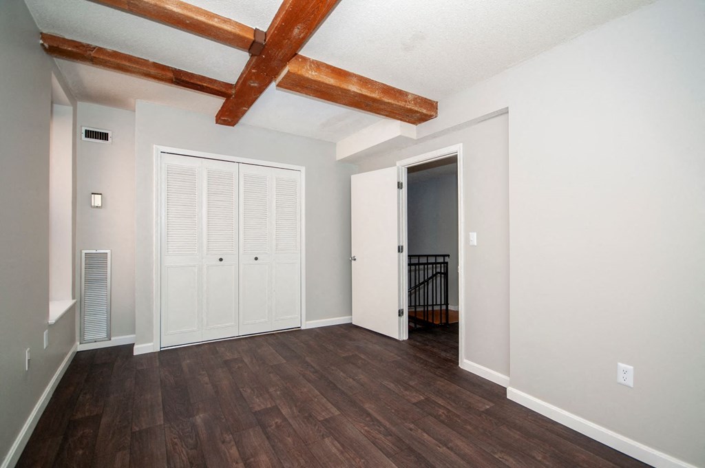 an empty living room with wood floors and ceiling with exposed beams