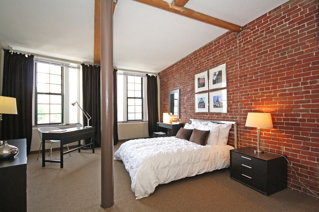 a bedroom with a bed and a brick wall