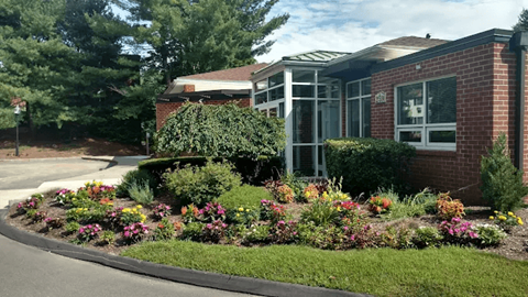 A red brick building with a green bush in front.