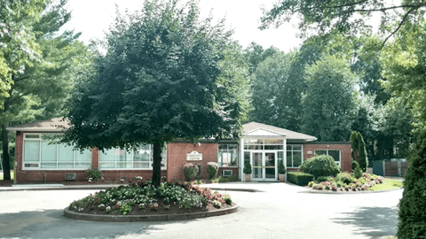 A building with a landscaped front yard and trees in the background.