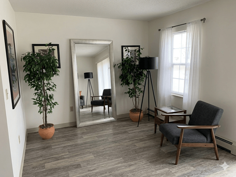 A living room with a grey chair and a potted plant.