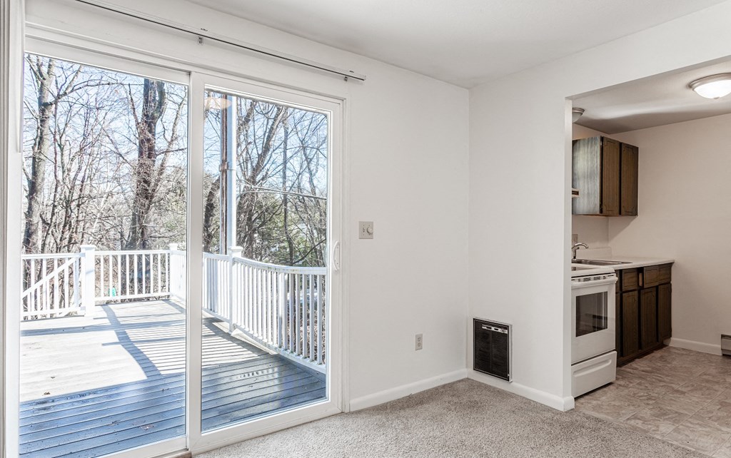A room with a deck and a kitchen area.