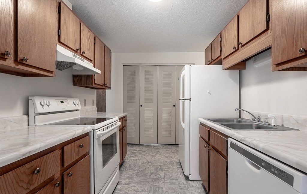 A kitchen with white appliances and wooden cabinets.