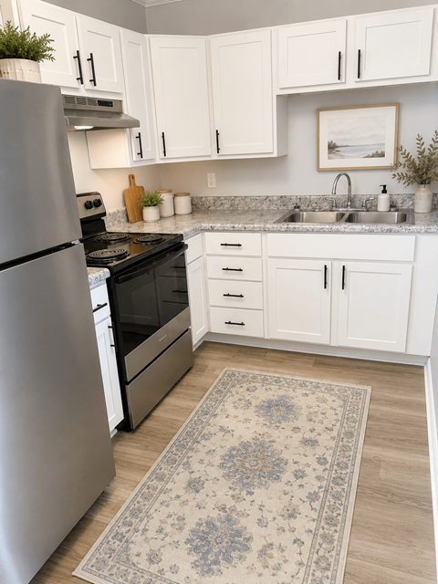 A kitchen with a refrigerator, sink, and cabinets.