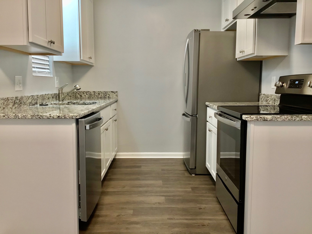 A kitchen with a refrigerator, oven, and sink.