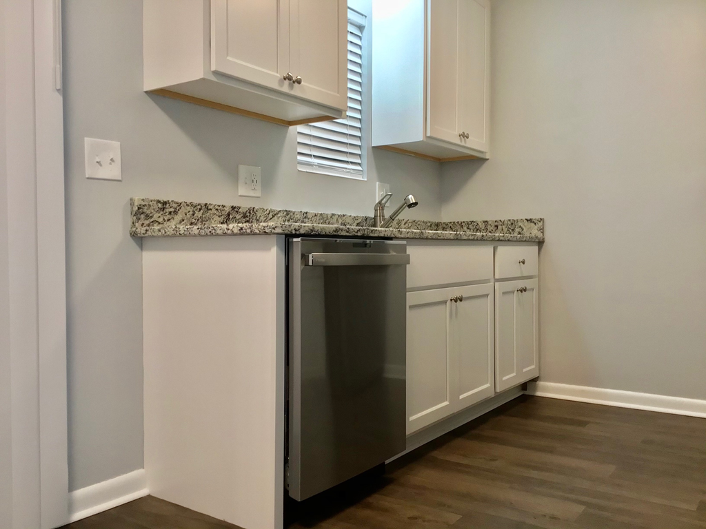 A kitchen with a granite countertop and white cabinets.