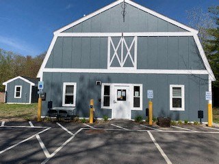 the front of a blue barn with a parking lot