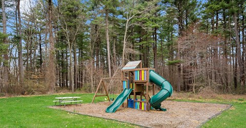 A playground with a green slide and a wooden structure.