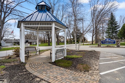 A gazebo with a blue roof is surrounded by a brick walkway.