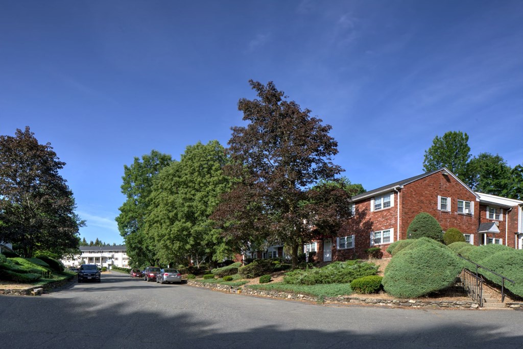 A residential area with a red brick building and green trees.