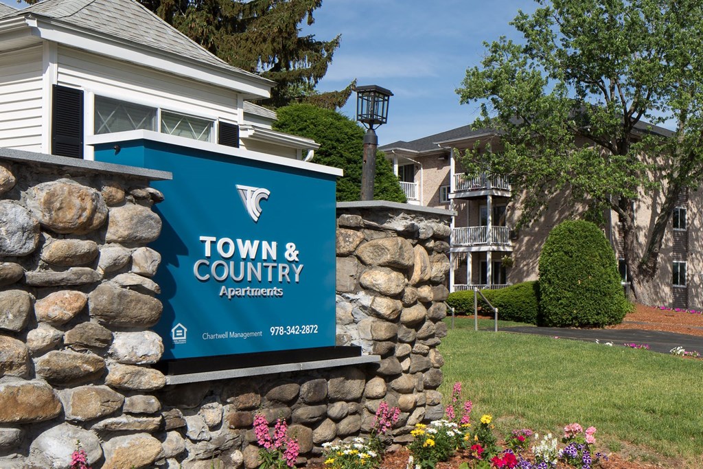 A sign for Town & Country Apartments is displayed on a stone wall.