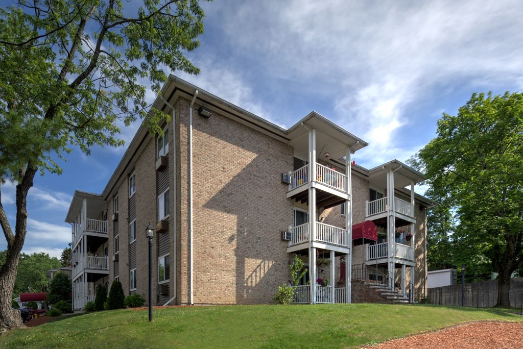 A large apartment building with a balcony and a red awning.