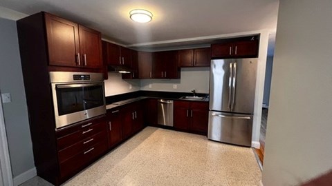 A kitchen with dark wood cabinets and stainless steel appliances.