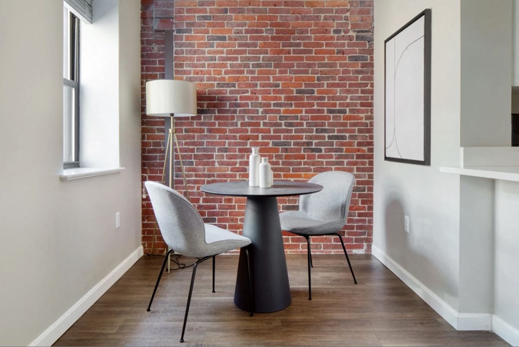 a small table with two chairs in front of a brick wall