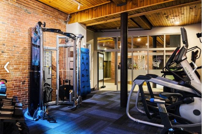 a gym with exercise equipment and a brick wall