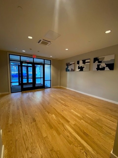 A room with wooden flooring and a large window with a view of a city.