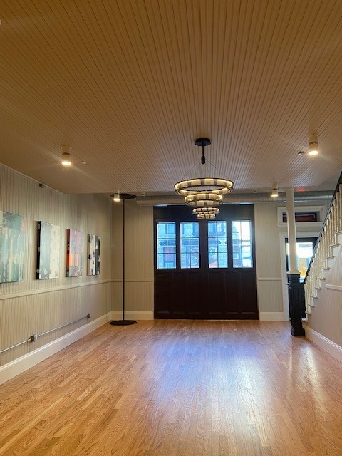 A room with wooden floors and a chandelier hanging from the ceiling.