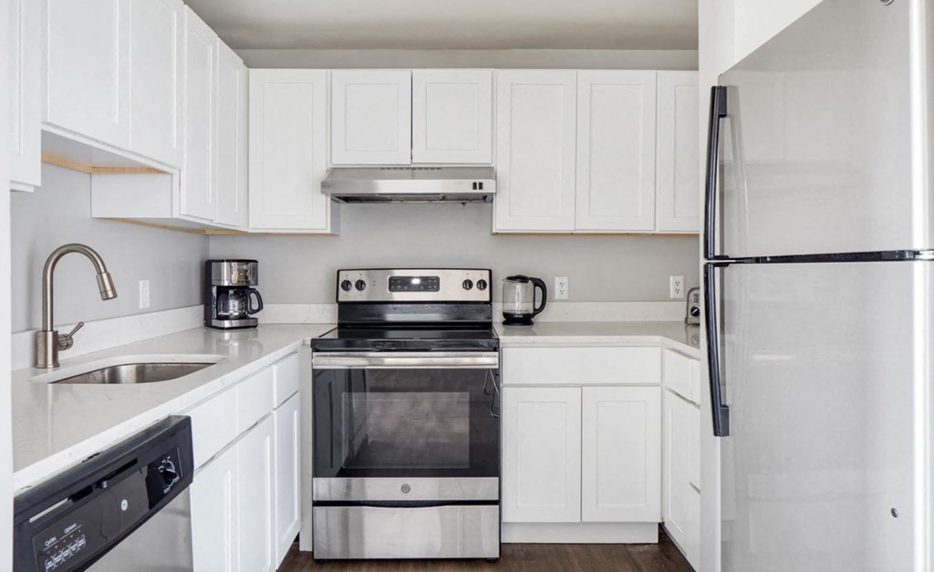 a white kitchen with stainless steel appliances and white cabinets