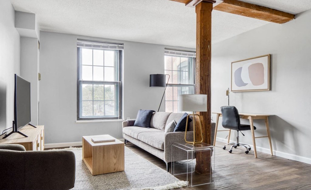 a living room with a couch and a desk and a tv