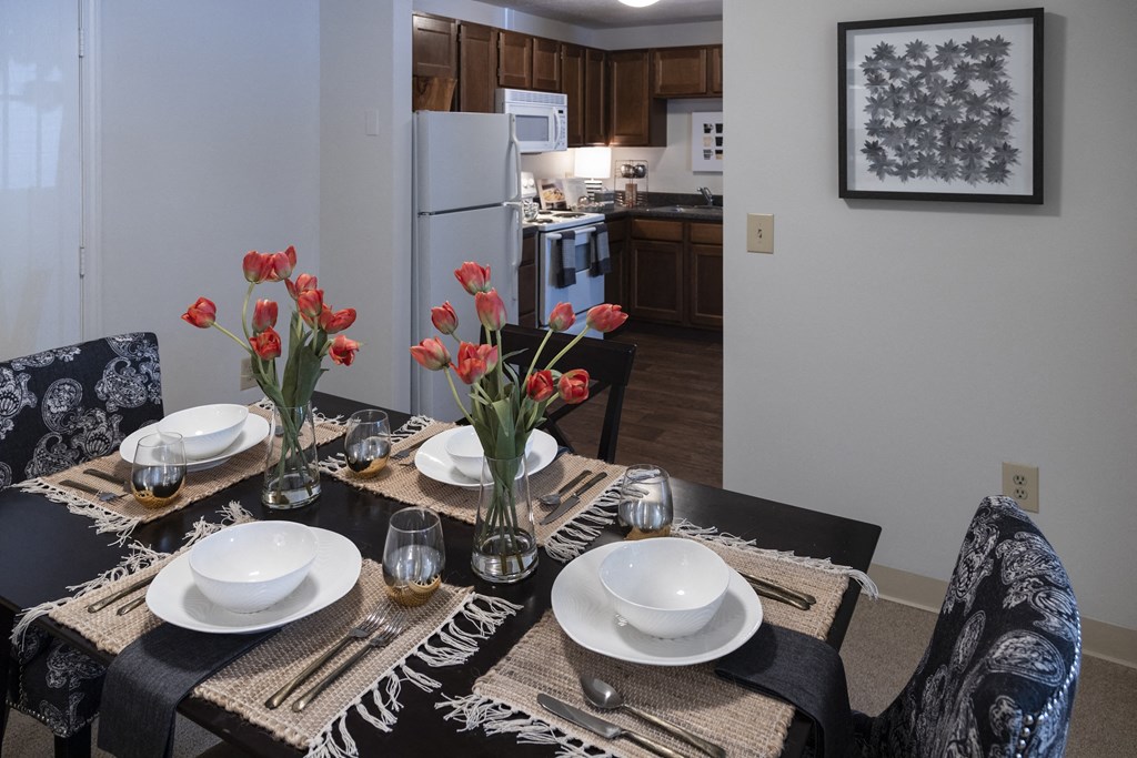 a dining room table with plates and flowers in a kitchen
