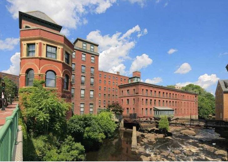 a large brick building with a river in front of it