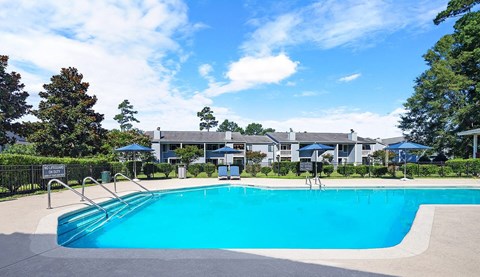A swimming pool surrounded by trees and a building in the background.
