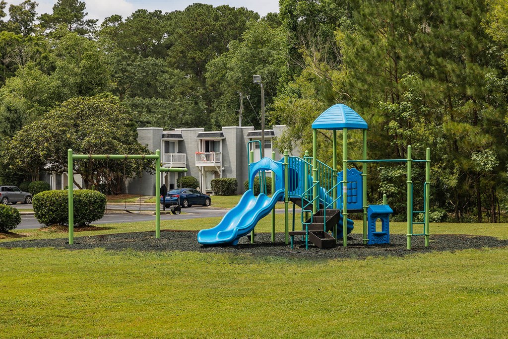 A playground with a blue slide and a green structure.