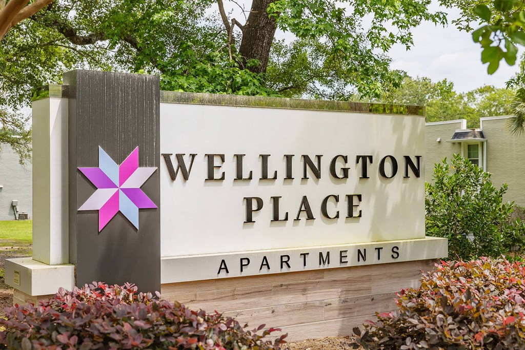 A sign for Wellington Place Apartments is shown in front of a building.