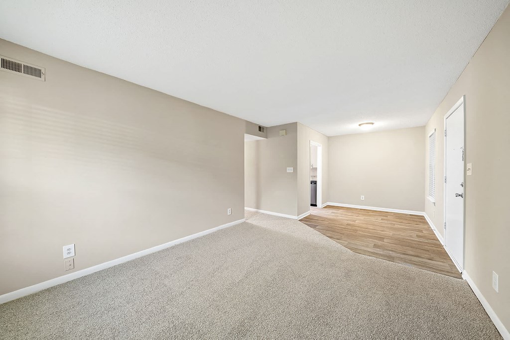 A room with a carpeted floor and a door on the right side.