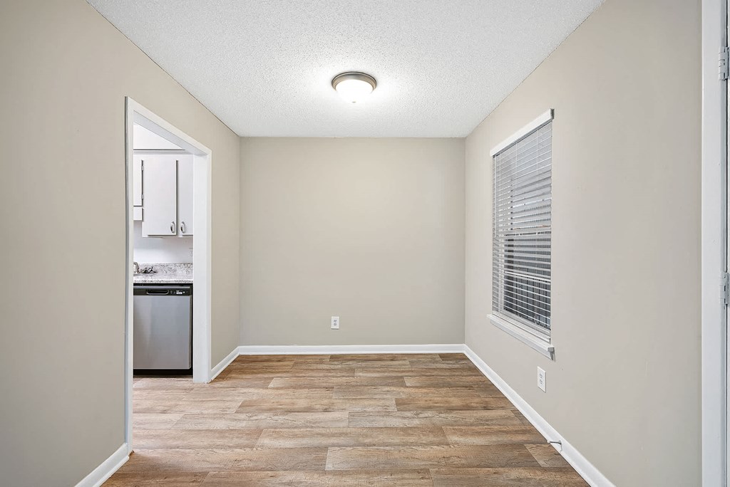 A kitchen area with a dishwasher and a window with blinds.