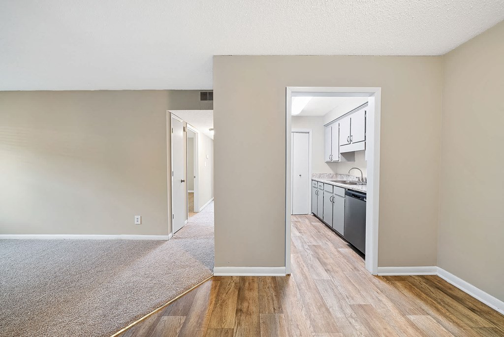 A kitchen area with a dishwasher and cabinets is visible through an open doorway.