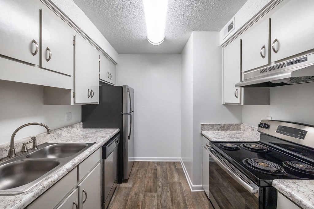 A kitchen with a black refrigerator, stove, and microwave.