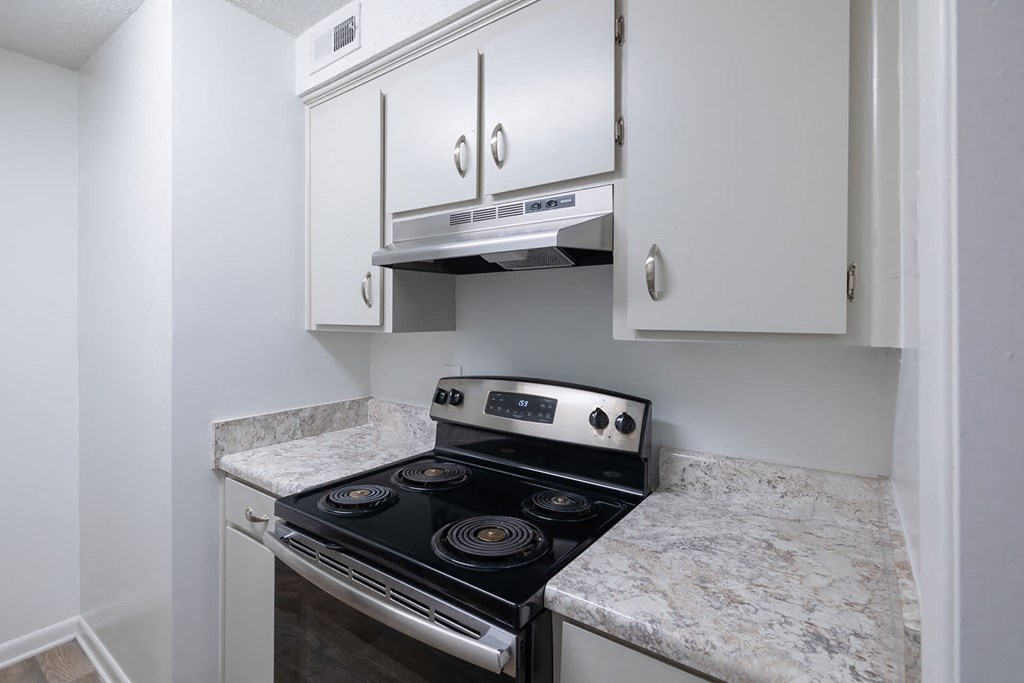 A stove with a stainless steel finish is in a kitchen with white cabinets.