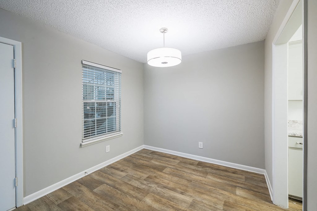A room with wooden flooring and a window with blinds.