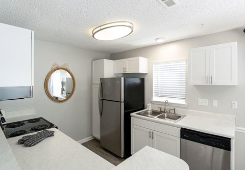 A kitchen with a black fridge and stove top oven.
