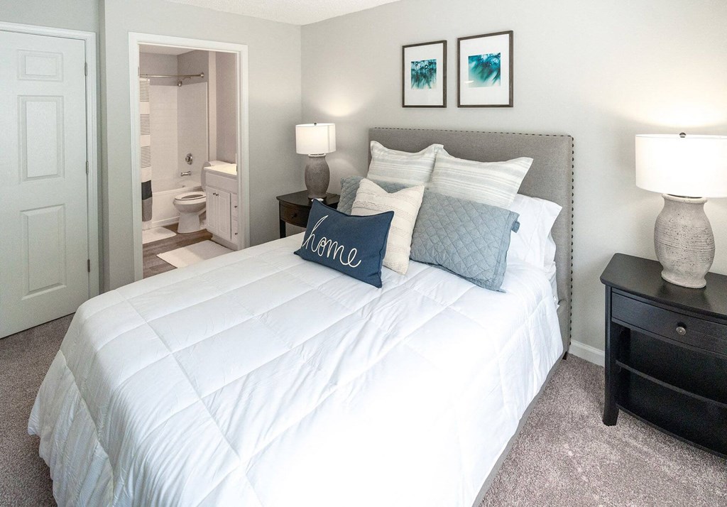 A bedroom with a large bed and two lamps.