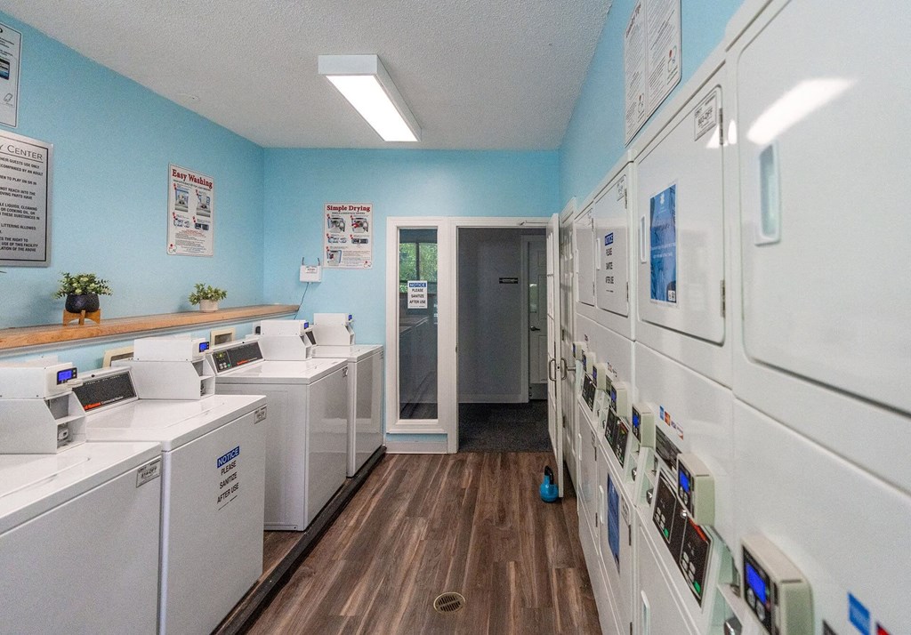 A laundromat with washers and dryers lined up.