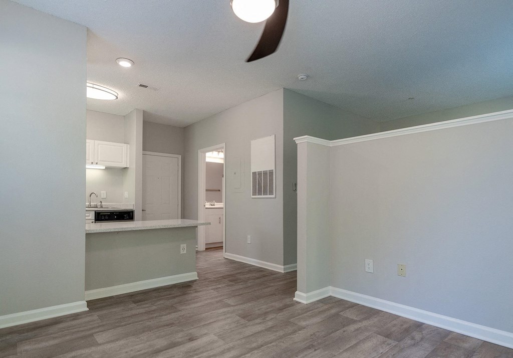 A room with a kitchen area and a fan on the ceiling.