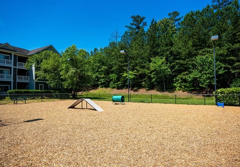 A playground with a seesaw and a slide in the middle of a sandy area.