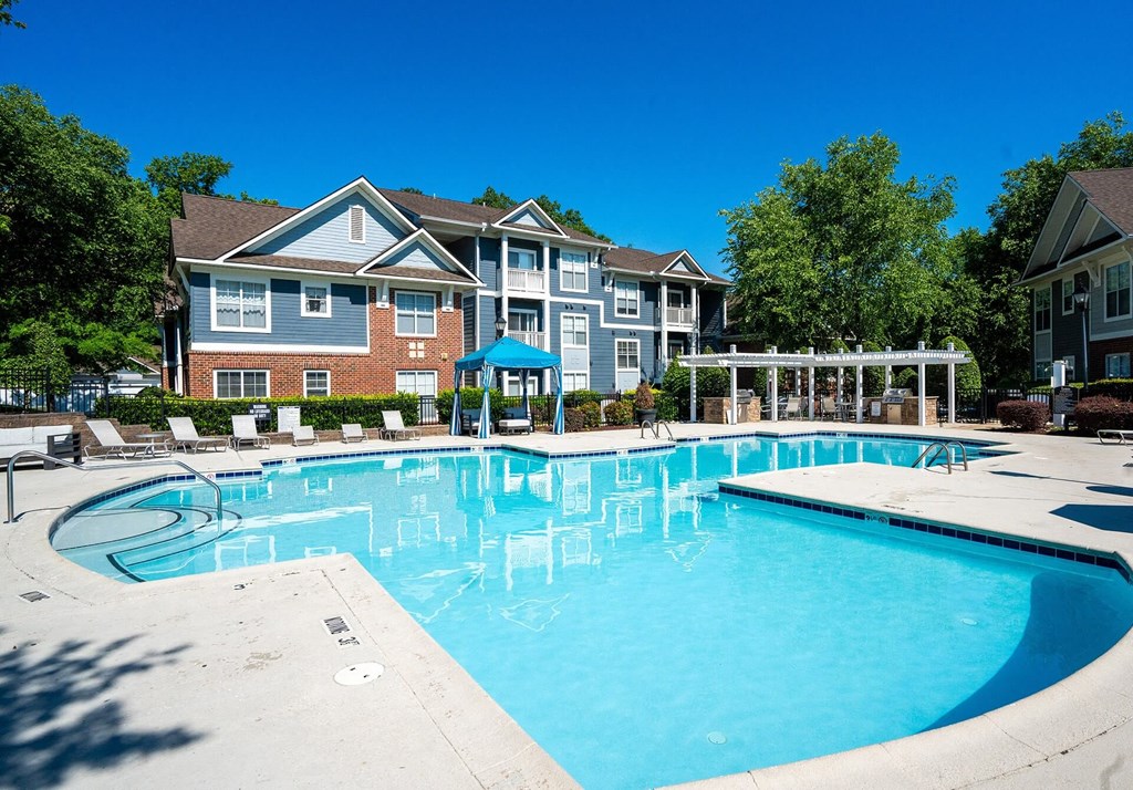A large swimming pool in front of a multi-story apartment building.