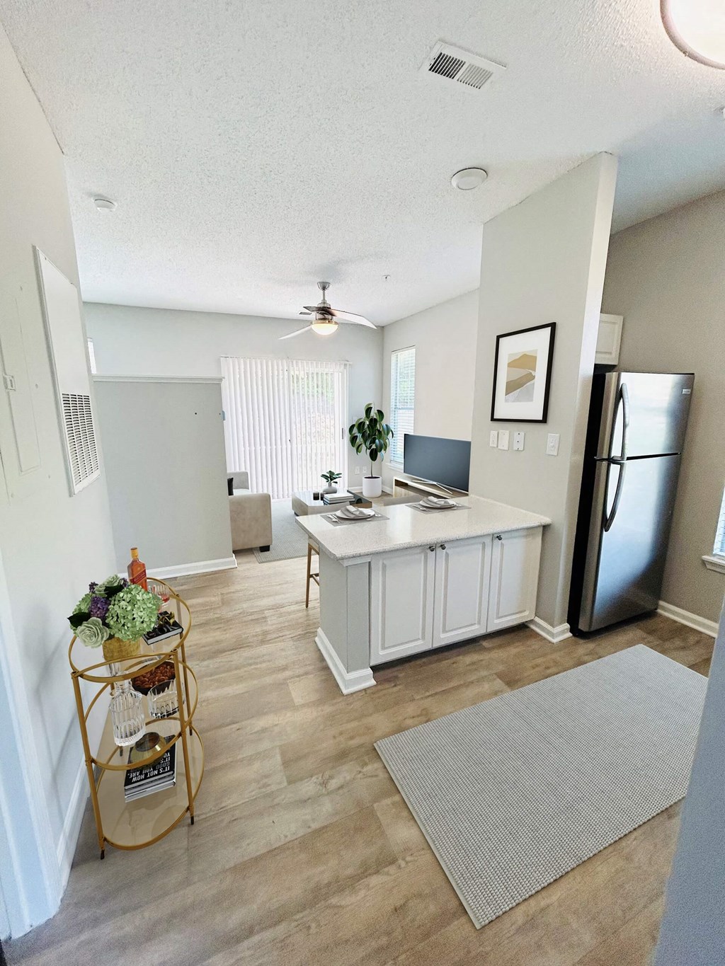 A kitchen with a refrigerator, a counter, and a plant on the counter.