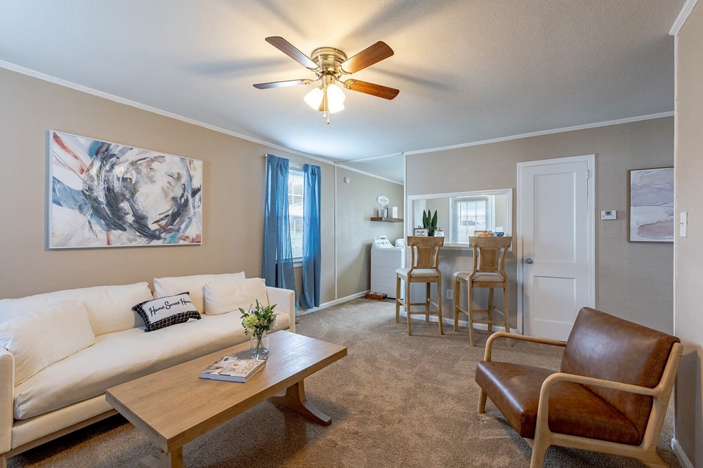 A living room with a white couch, a brown leather chair, and a wooden coffee table.